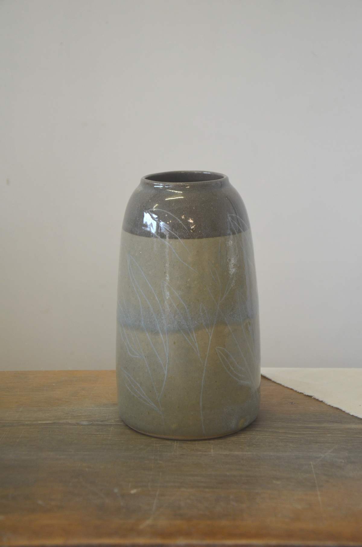 Vase gris-bleu à col foncé, décor de feuillages clairs.