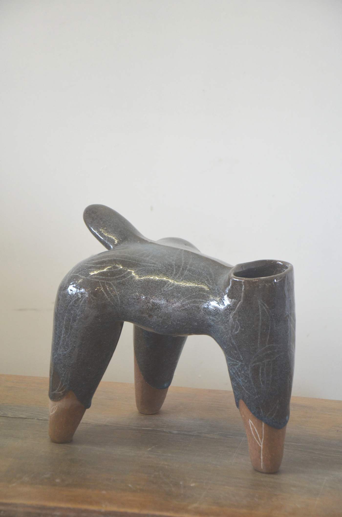 Pièce grise et brillante à quatre pieds bruns, posée sur une table en bois.